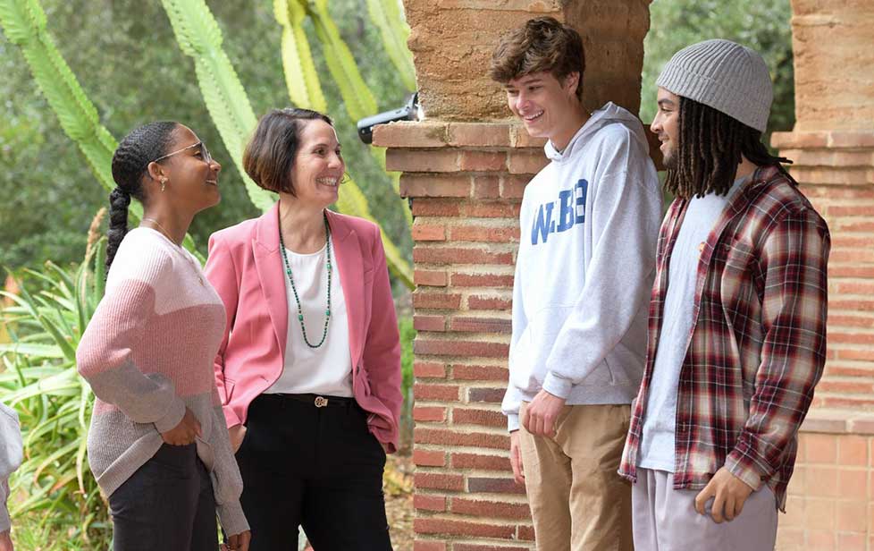 students and teacher talking outside on campus